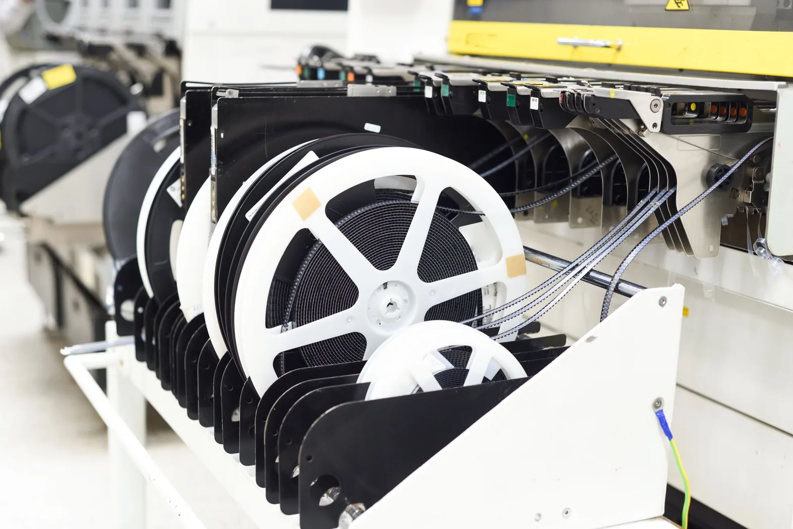 Reels of tape-packaged surface mount components loaded onto feeders on an SMT placement machine