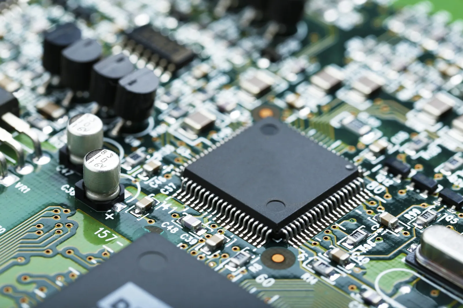 Close-up of an assembled printed circuit board with a fine-pitch integrated circuit, capacitors, and passive components