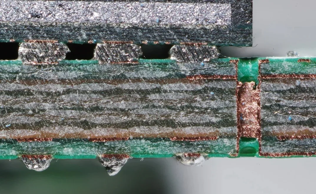 Microsection of a multilayer printed circuit board showing plated through holes, copper layers, and laminate structure
