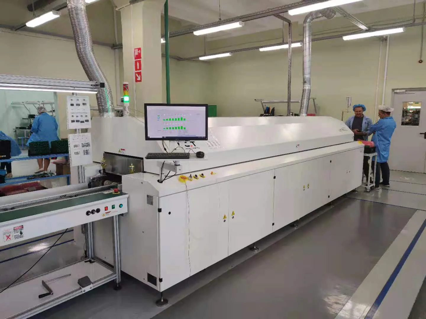 Reflow oven in a production area with an operator station and the reflow profile shown on a monitor